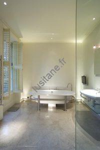 Vue d’un carrelage en pierre naturelle dans une salle de bain zen avec vasque en pierre